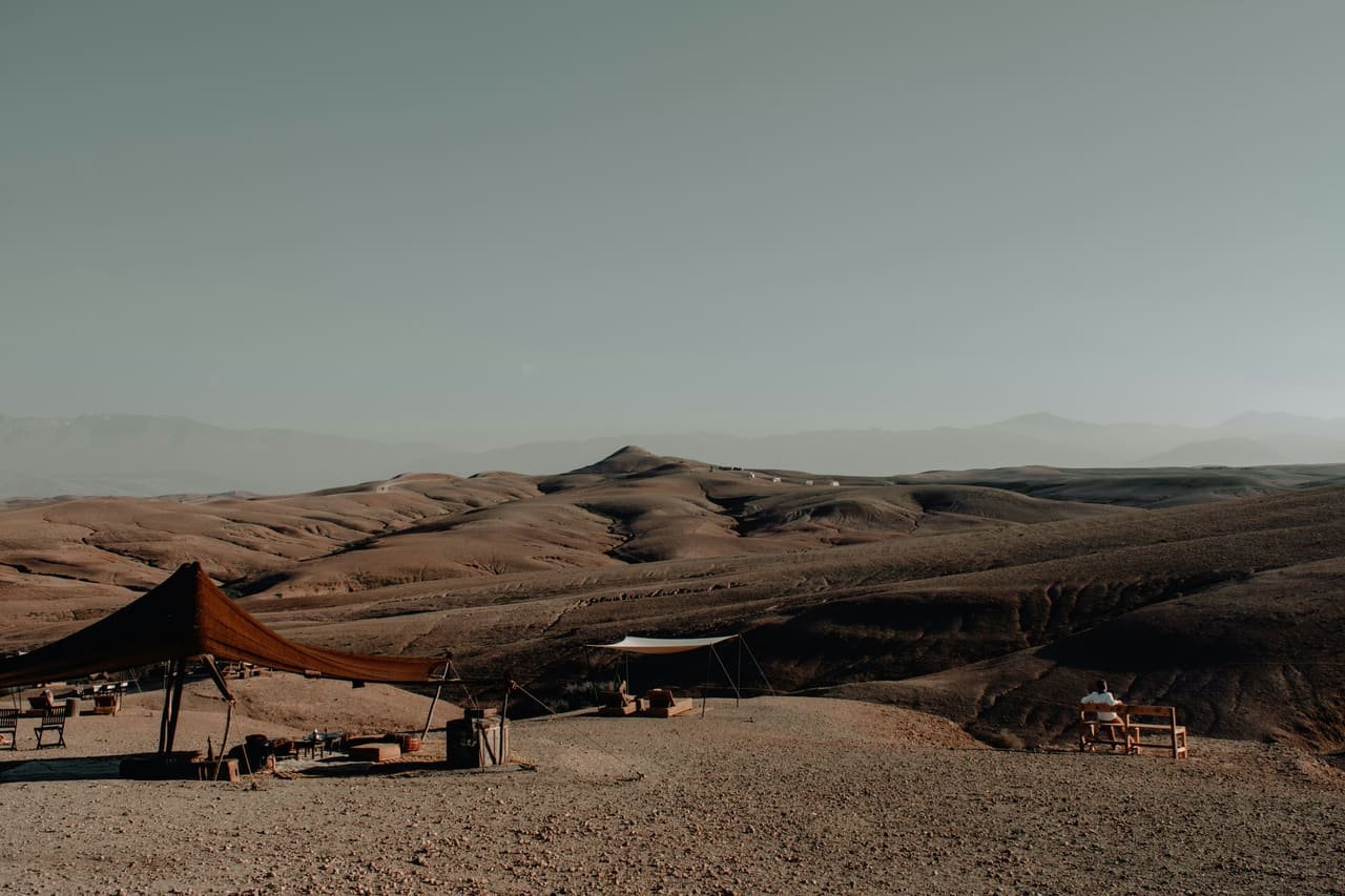 The bare stone hills of the Agafay desert with the High Atlas on the horizon